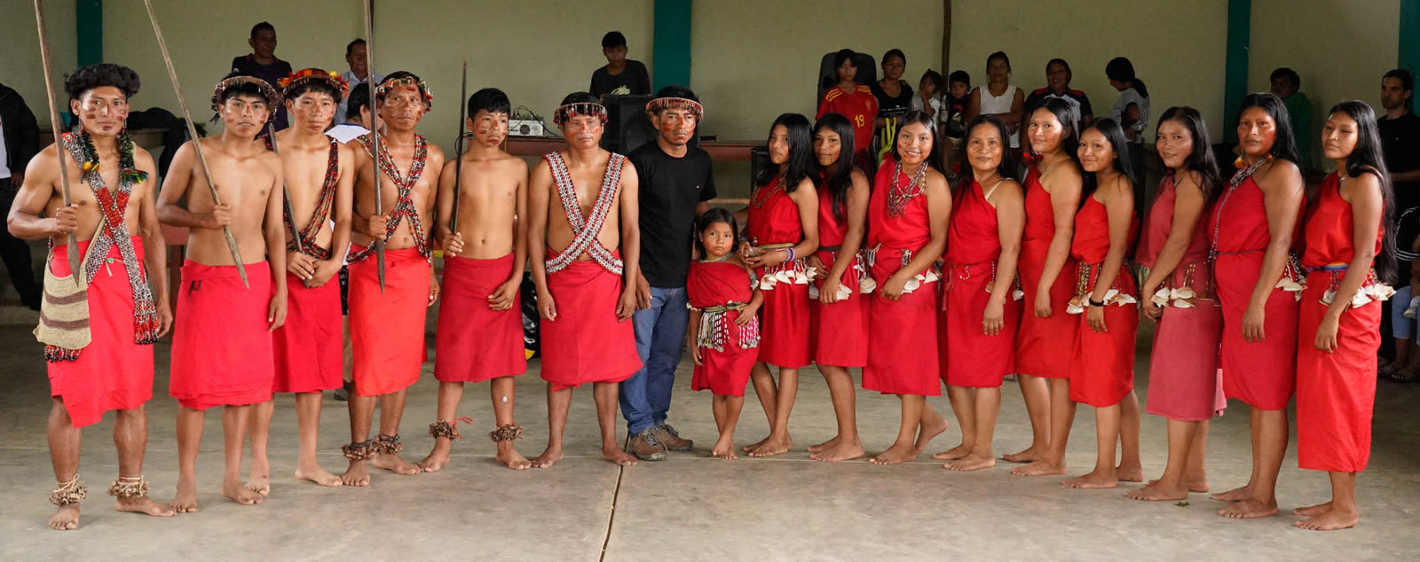 Awajún community members in traditional red dress standing in a line